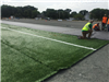 Men working on artificial turf infield