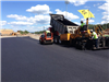 Workers on large machines laying the track material
