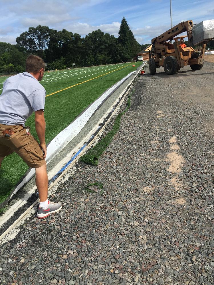 Person laying last of artificial turf