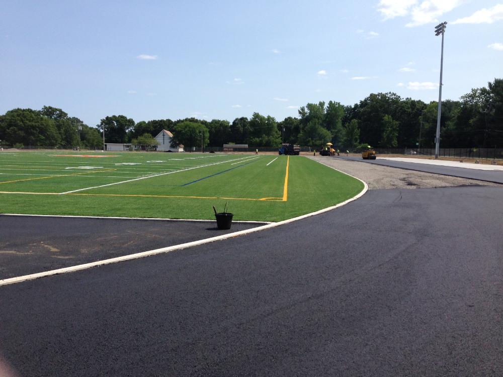 Workers on large machines laying the track material