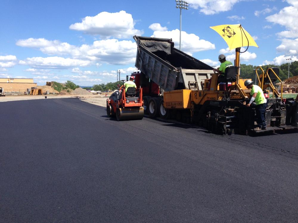 Workers on large machines laying the track material