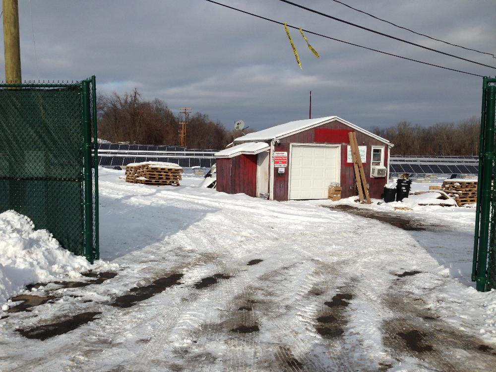 View of the building and solar panels from the gate at the Main Street Solar Farm